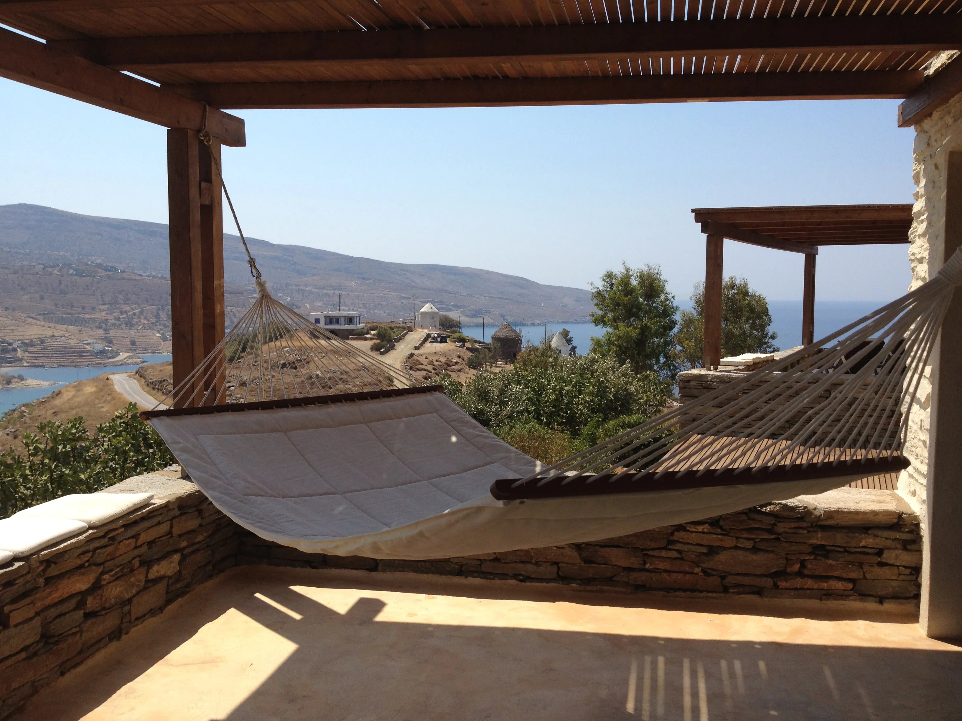 Hammock on the shaded stone terrace at Zephyros Stone Villa, looking out over Koundouros bay and the Aegean