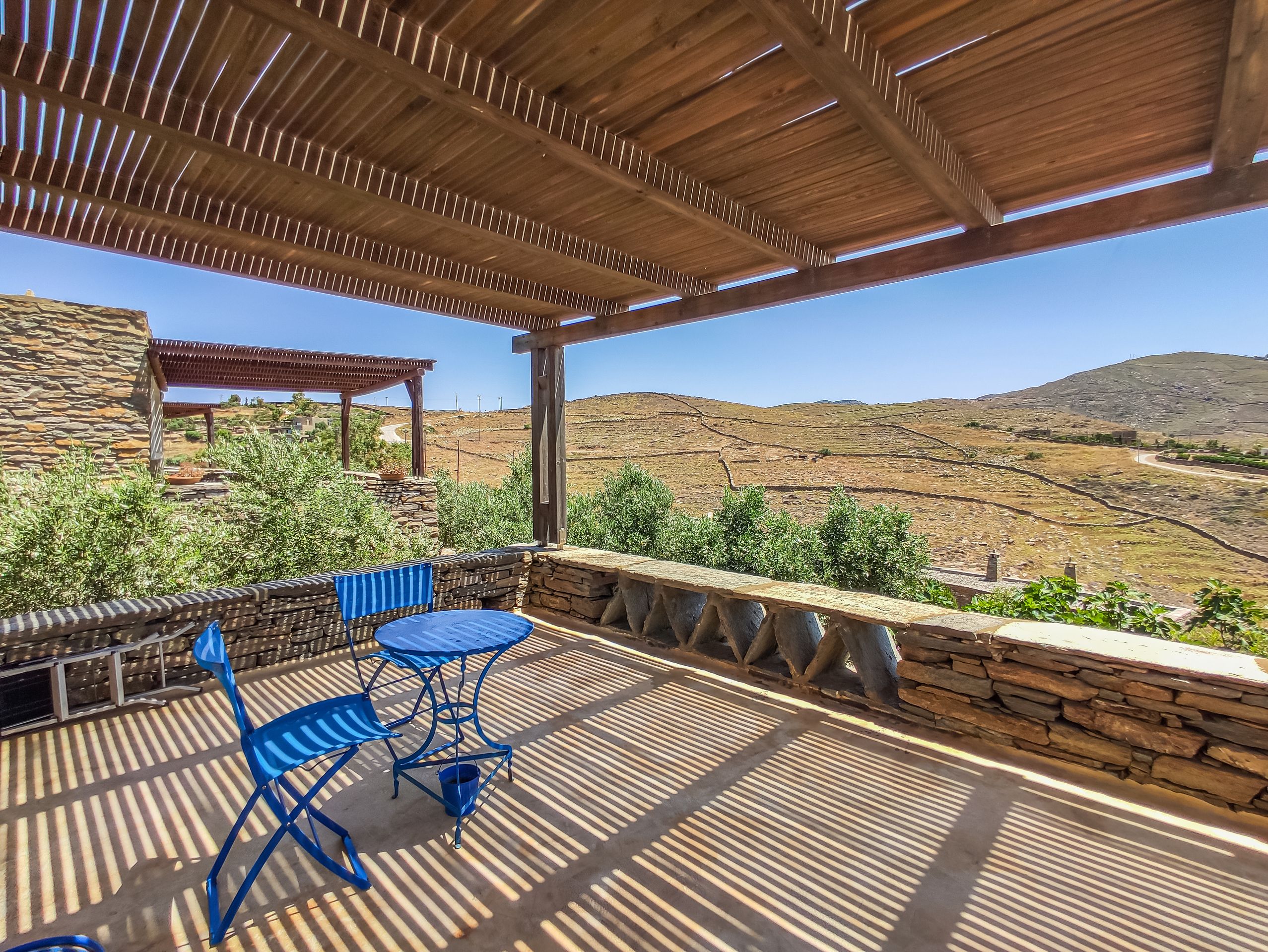 Pergola terrace with blue chairs looking out over the hill and Koundouros bay