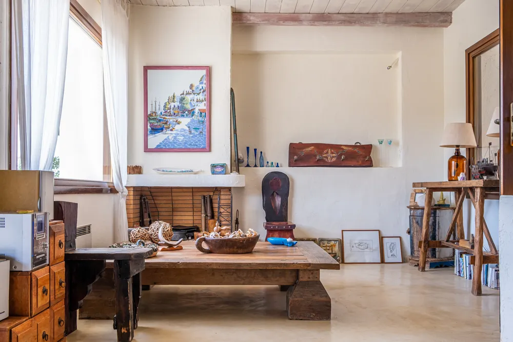 Sitting area with a heavy wood coffee table, whitewashed walls, a fireplace, and a harbour painting above it
