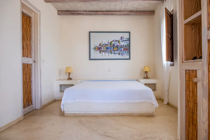 Master bedroom with king bed, stone walls, and sea-view windows