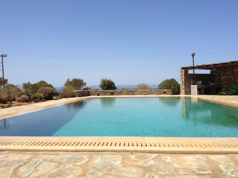 Shared swimming pool set into the stone terrace, with the Aegean beyond